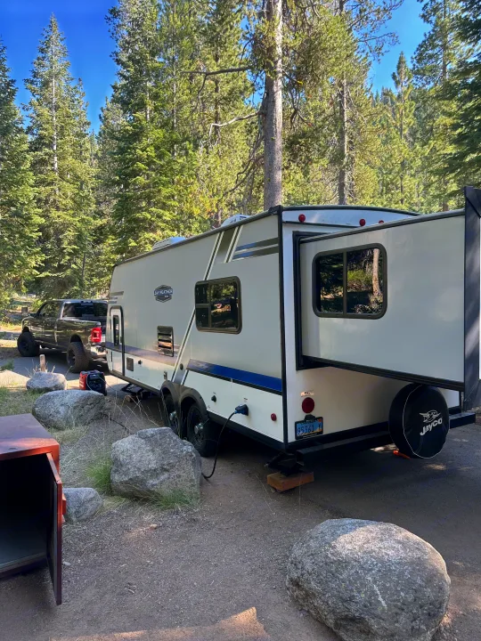 RV rental at a scenic forest campsite: A travel trailer with a slide-out is parked next to a pickup truck.. Jayco Jay Flight 2018