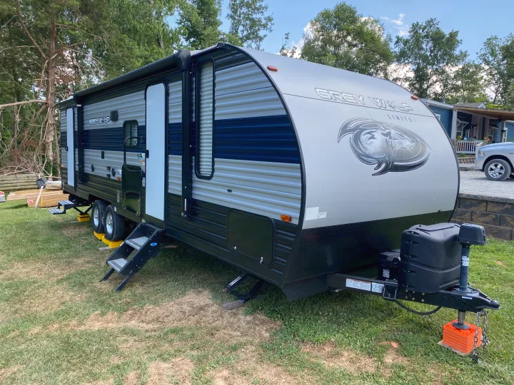 Modern Grey Wolf travel trailer RV rental, parked on green grass with steps extended. Perfect for outdoor adventures.. Forest River Cherokee Grey Wolf 2021