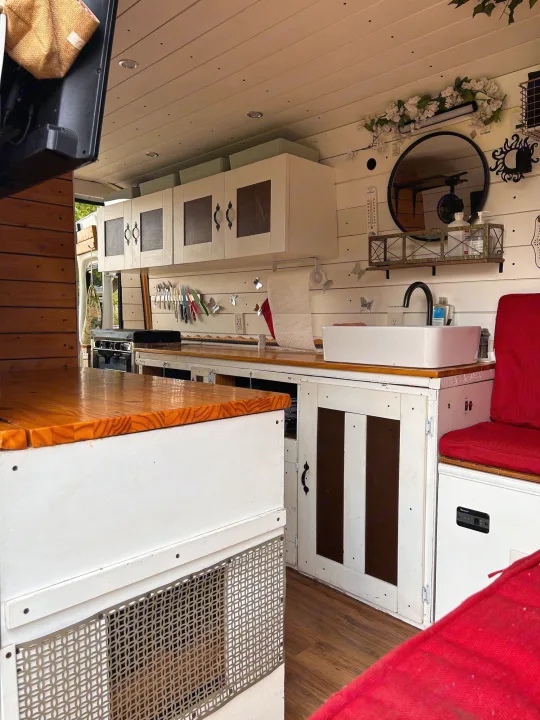 Spacious RV rental interior with a well-equipped kitchen featuring white cabinetry, wood counters, sink, and red seating.. Ram Dodge Promaster 3500 2019