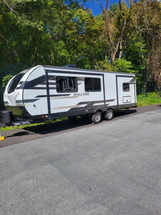 White Mallard travel trailer, a great RV rental for your next adventure. Parked on asphalt.. Heartland RVs Mallard 2023