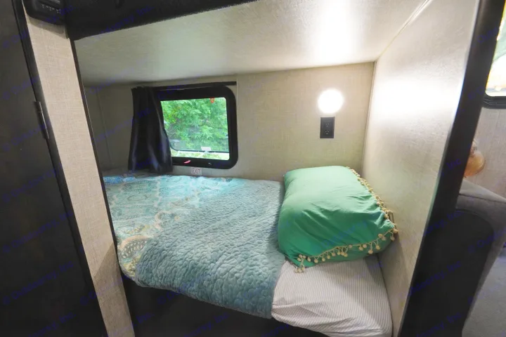 Cozy bunk bed in an RV rental, featuring a teal comforter, green pillow, window view, and reading light.. Jayco Jay Flight 2022