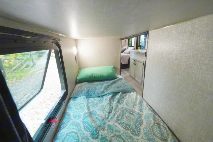 Experience an RV rental: cozy bunk bed area with an open window offering outdoor views, plus a peek into the main living space.. Jayco Jay Flight 2022