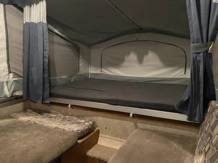 Inside this pop-up camper RV rental: a large bed, seating, and curtains for comfort during your next camping trip.. Forest River Palomino 2010