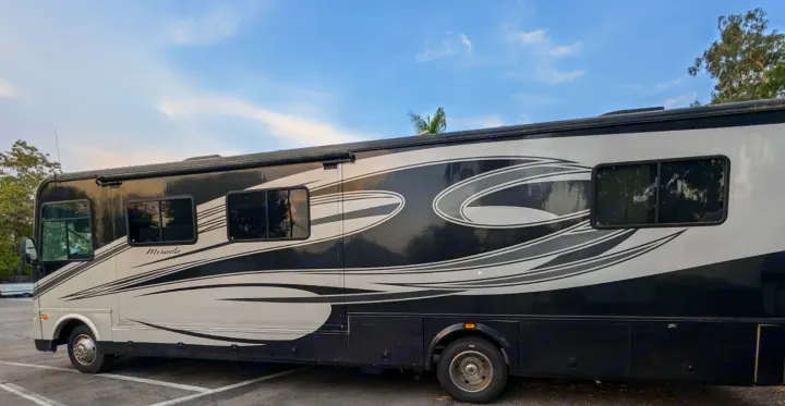 Side view of a large, black and white Mirada RV rental with unique graphic stripes, parked outdoors for your next travel adventure.. Coachmen Mirada 2009