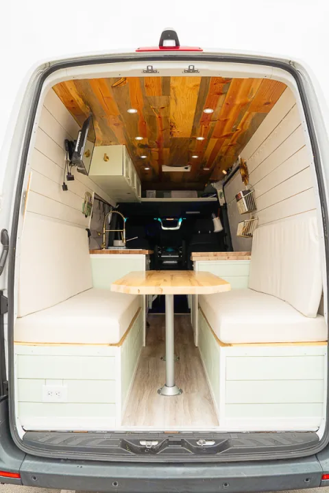 Stylish **RV rental** van conversion interior showing a cozy dining area, wood ceiling, and compact kitchen setup.. Mercedes-Benz Sprinter 2019