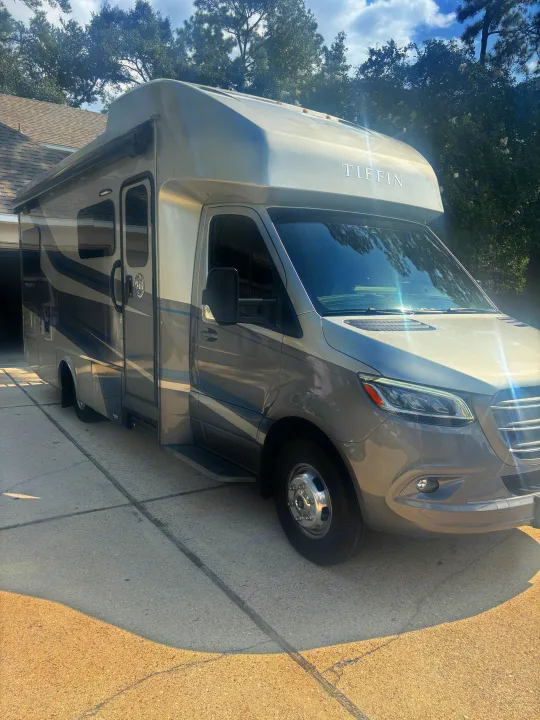 A sleek, two-toned gray Tiffin Wayfarer Class C RV rental is parked on a sunny driveway, ready for your next adventure.. Wayfarer Wayfarer Motorhome 2021