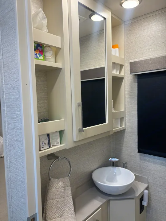 RV rental bathroom featuring a vessel sink, mirrored cabinet with toiletries, a light, and towel. Compact and practical design.. Wayfarer Wayfarer Motorhome 2021