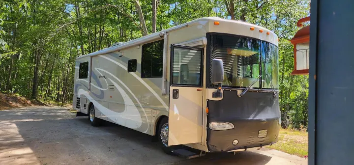 Spacious RV rental parked in a sunny, wooded setting, ready for your next outdoor travel adventure.. Winnebago Journey 2006