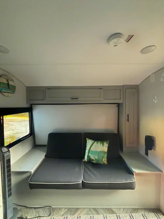 Cozy RV rental interior featuring a sofa, overhead cabinets, and clever space-saving design for comfortable travel.. Forest River Wildwood FSX Plantium 2022