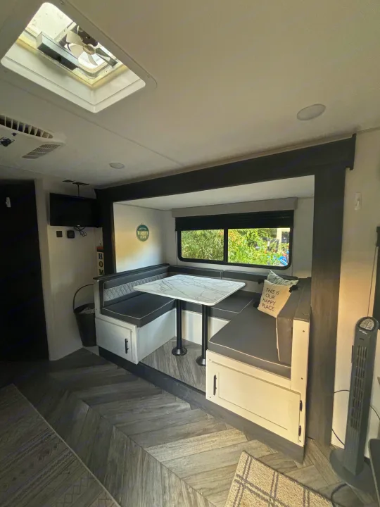Explore this RV rental: Modern dinette, window view, and herringbone floors create a cozy space.. Forest River Wildwood FSX Plantium 2022