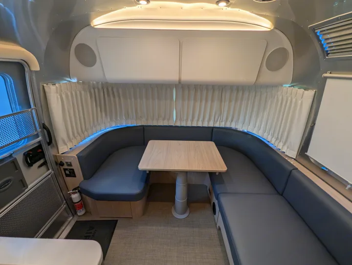 Interior of a modern RV rental, featuring a U-shaped dinette with comfortable seating, ideal for travel.. Airstream Globetrotter 2024