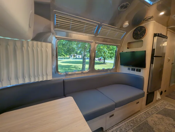 Cozy Airstream RV rental interior with dining area, kitchen amenities, and scenic window views for comfortable travel.. Airstream Globetrotter 2024