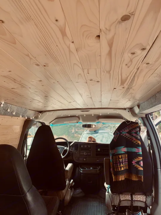 Interior of an RV rental, featuring a custom wood-paneled ceiling, string lights, and the spacious front cabin.. Gmc Savanna 2016