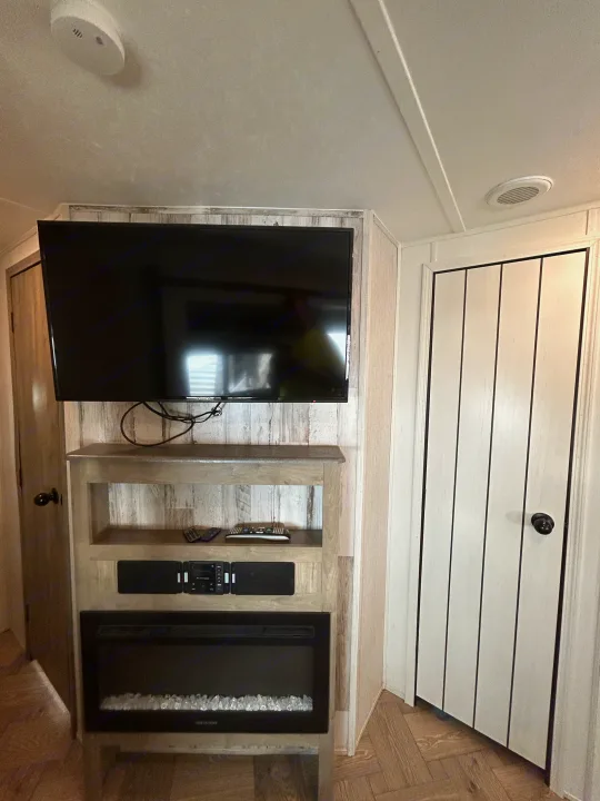Inside a comfortable **rv rental**: modern entertainment setup with TV, audio, electric fireplace, and cozy wood details.. Palomino Puma 2022