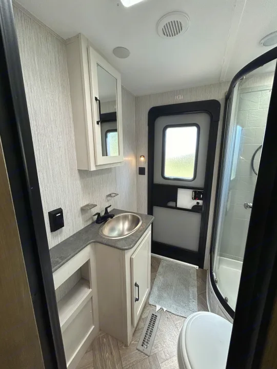 Modern RV rental bathroom with vanity, sink, mirror cabinet, shower, and toilet for compact living.. Palomino Puma 2022