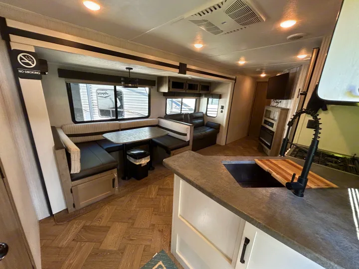 Experience this cozy modern RV rental interior, featuring a dining booth, kitchen, and comfortable living area.. Palomino Puma 2022