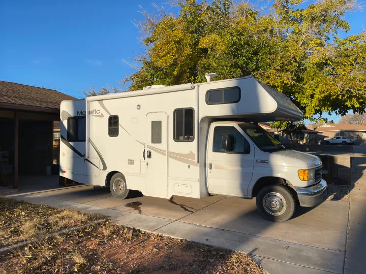 White Majestic RV rental parked in a sunny driveway under a blue sky, ready for road trip adventures.. Four Winds Majestic 2007