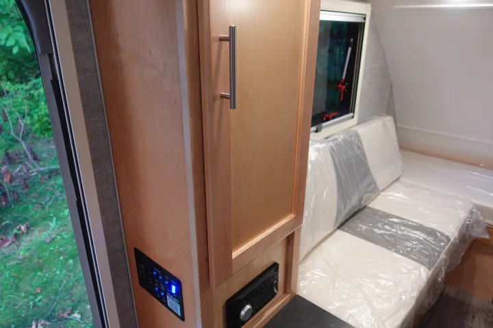 Cozy RV rental interior shows wooden cabinet, control. Little Guy Mini-Max 2024