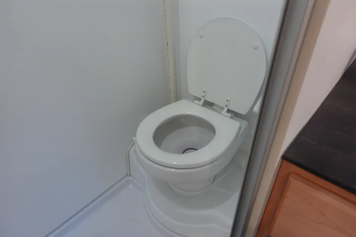 Inside an RV rental: a compact white toilet and shower pan, typical of an RV wet bath.. Little Guy Mini-Max 2024