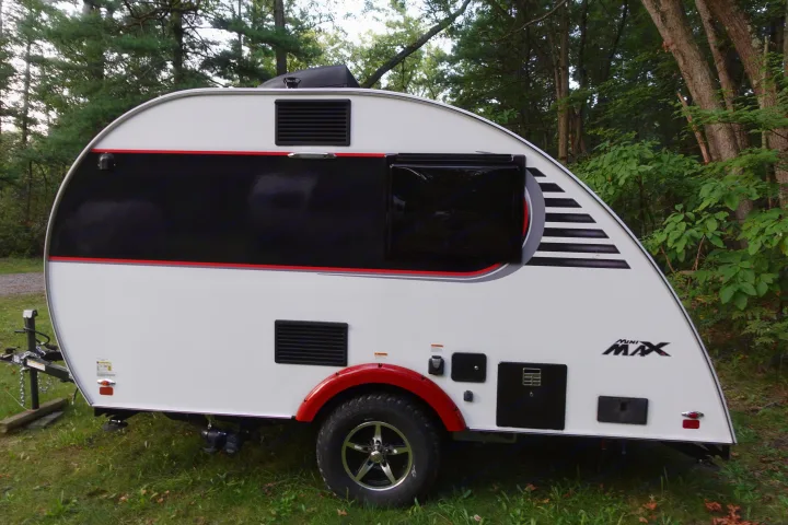 A modern white and black Mini Max teardrop travel trailer parked outdoors. Consider it for your next RV rental camping trip!. Little Guy Mini-Max 2024