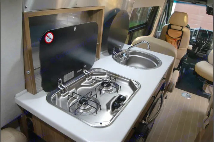 Compact kitchenette in this RV rental, featuring a two-burner stove and sink. Perfect for mobile living and travel.. Airstream Interstate 2017