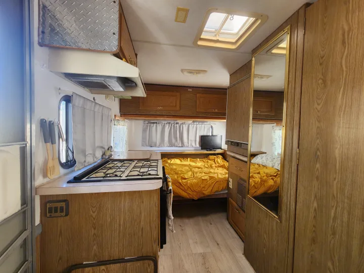 Step inside this comfortable RV rental! View of kitchen, bedroom, and living area, complete with wood accents and skylight.. Fleetwood Wilderness 1991