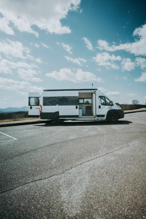 White RV rental camper van parked at a scenic mountain overlook with doors open, showcasing its interior.. Noke Van Co. Rory 2021