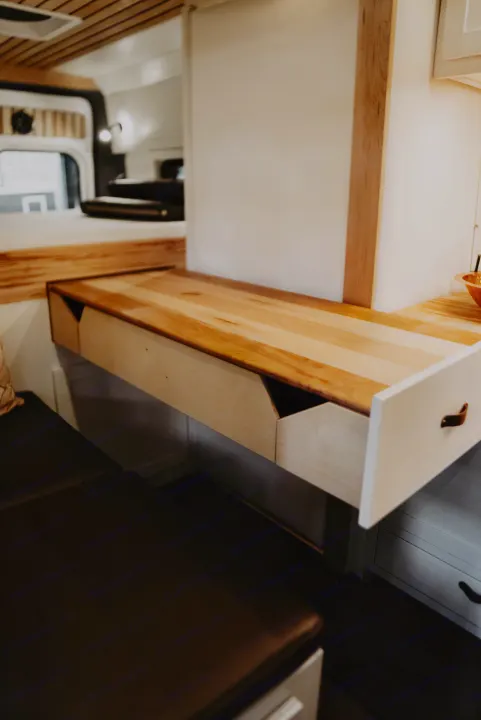RV rental: A clever light wood pull-out desk with an open storage drawer and cozy bench seating maximizes this camper's space.. Noke Van Co. Rory 2021