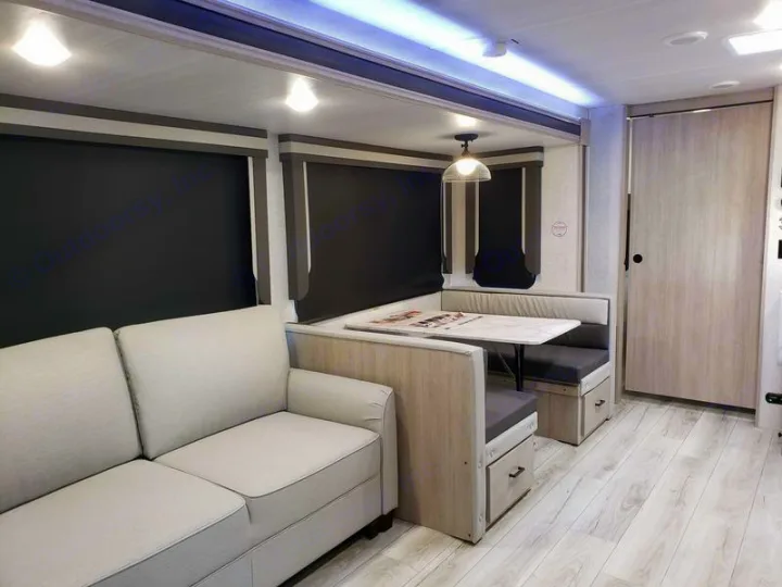 Spacious, modern RV rental interior featuring a light sofa, dining dinette, and light wood flooring, ready for your travels.. East to West Alta 2024