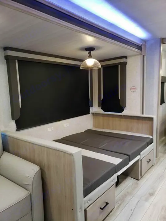 RV rental interior: a versatile bed/seating area with storage drawers, blackout shades, and overhead lighting.. East to West Alta 2024