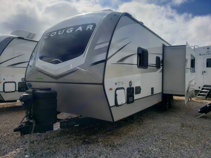 This RV rental photo shows a modern Cougar Half Ton travel trailer with an open slide-out, perfect for a spacious trip.. Keystone RV Cougar 2024