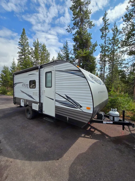This white and gray Salem Cruise Lite travel trailer is ready for your RV rental adventure amidst pine trees.. Forest River Salem Cruise Lite 2017