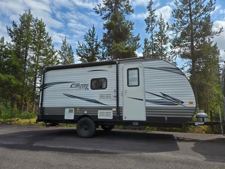A white Salem Cruise Lite travel trailer, a perfect RV rental, parked among tall pine trees.. Forest River Salem Cruise Lite 2017