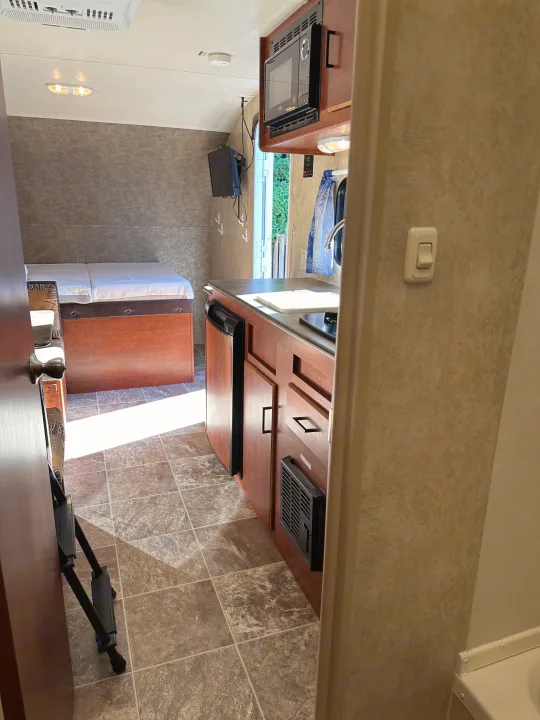rv rental interior: From the doorway, a compact kitchen with appliances and a cozy bed area are visible. Bright and functional RV space.. Forest River Salem Cruise Lite 2017