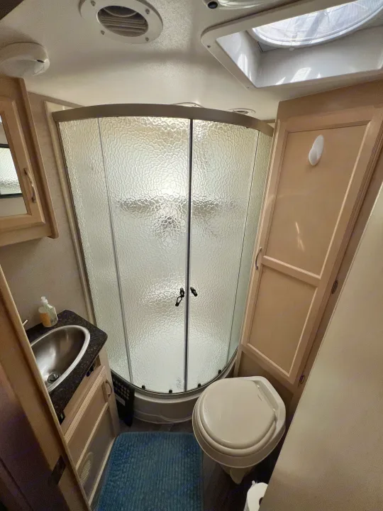 Compact RV rental bathroom, featuring a curved shower, toilet, and stainless steel sink. Essential amenities for your trip.. Winnebago Micro Minnie 2306BHS 2019