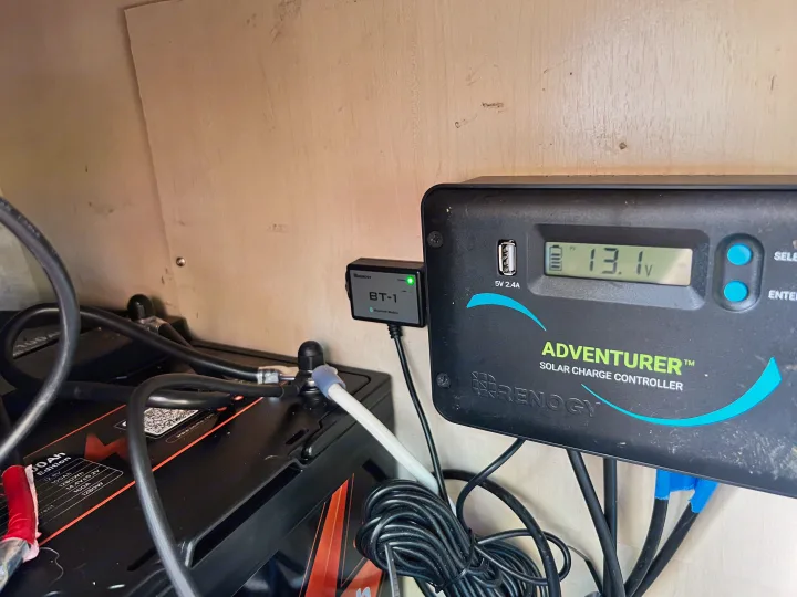 Inside an RV rental: Renogy Adventurer solar charge controller (13.1V), BT-1 module, and 100Ah battery for off-grid power.. Winnebago Micro Minnie 2306BHS 2019