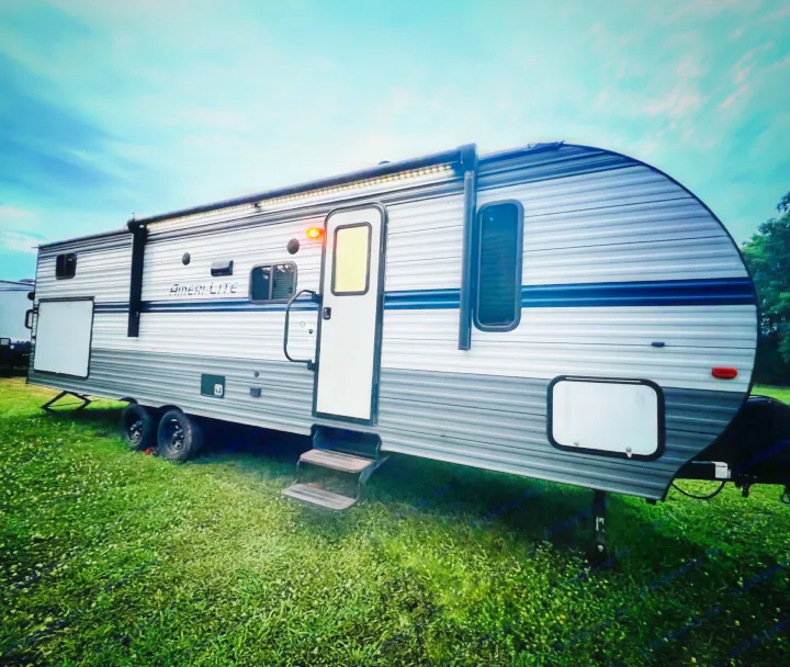 This Ameri-Lite travel trailer RV rental, parked on grass with lights on, is ready for your next adventure.. Gulf Stream Gulf Stream 2021