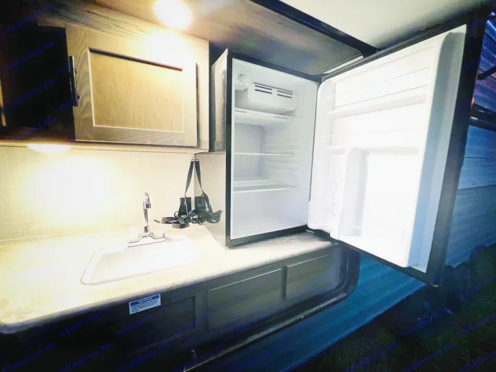 Explore this RV rental's compact kitchen: open mini-fridge, sink, and overhead storage for your road trip comfort.. Gulf Stream Gulf Stream 2021