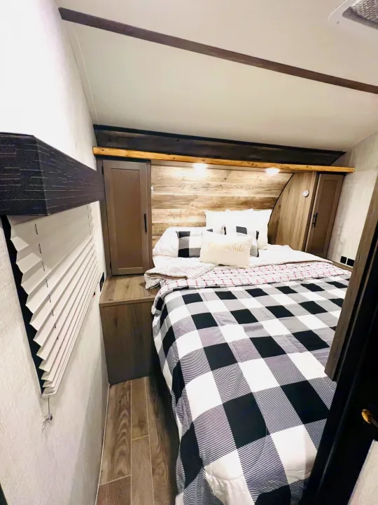 Cozy RV rental bedroom featuring buffalo plaid bedding, built-in storage, and warm lighting for a comfortable stay.. Gulf Stream Gulf Stream 2021