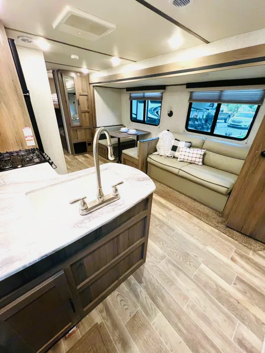 Modern RV rental interior: kitchen with sink, dinette, sofa, and light wood floors. Bright and functional space.. Gulf Stream Gulf Stream 2021