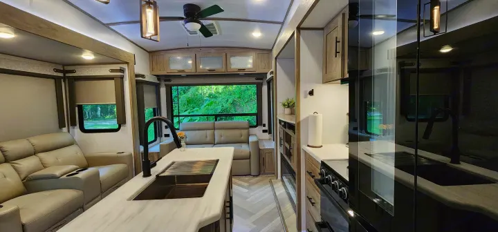 Inside a modern rv rental: a light-colored living area with leather sofas, an island kitchen, and big windows.. Forest River Hemisphere 2022