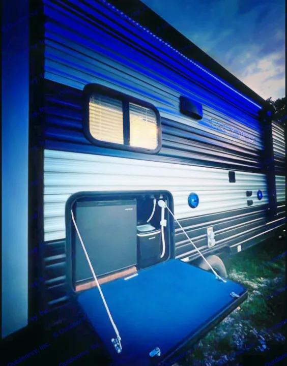 This RV rental features a unique outdoor kitchen with a fridge and faucet, illuminated by blue accent lights.. Forest River Cherokee Grey Wolf 2020