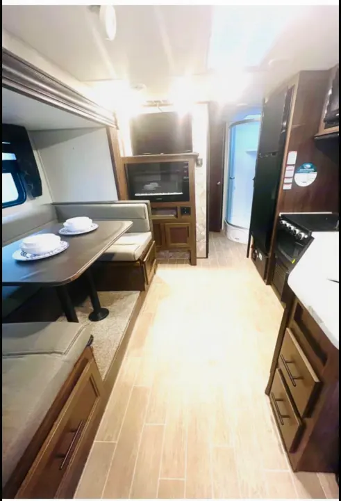 Cozy rv rental interior: view of dinette with place settings, kitchen, and bathroom. Bright and inviting.. Forest River Cherokee Grey Wolf 2020