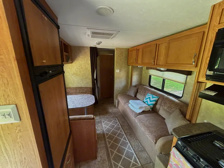 RV rental interior shows a comfortable living area with a sofa, dining booth, kitchen, and doorway to a private space.. Jayco Jay Flight 2010
