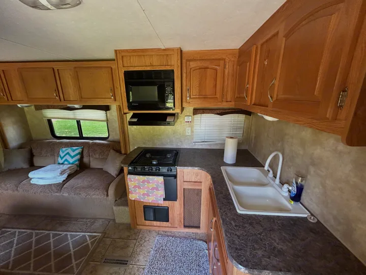 Cozy RV rental kitchen features stove, sink, microwave, plus a sofa. Ideal for travel and camping adventures.. Jayco Jay Flight 2010