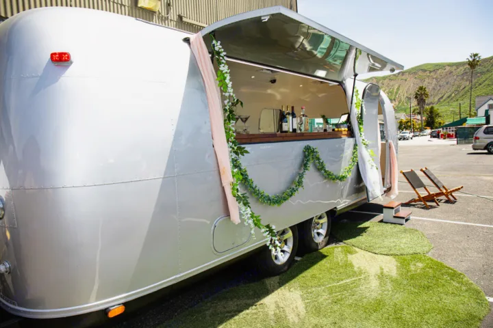 This Airstream RV rental, serving as a charming mobile bar, offers drinks and lounge seating for outdoor events.. Airstream custom 1973