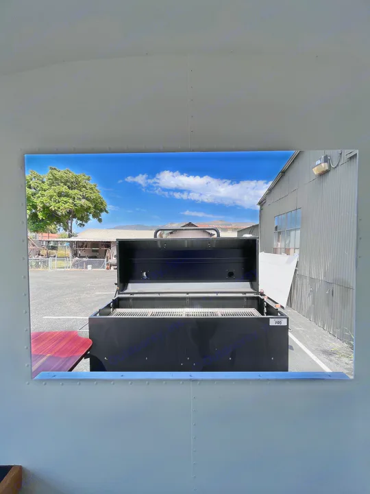 Looking out from an rv rental, an open black BBQ grill sits ready for outdoor cooking under a blue sky.. Airstream Custom 1957