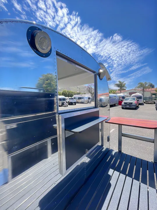 Experience unique outdoor living with this Airstream-style RV rental, featuring a wide serving window and integrated patio.. Airstream Custom 1957