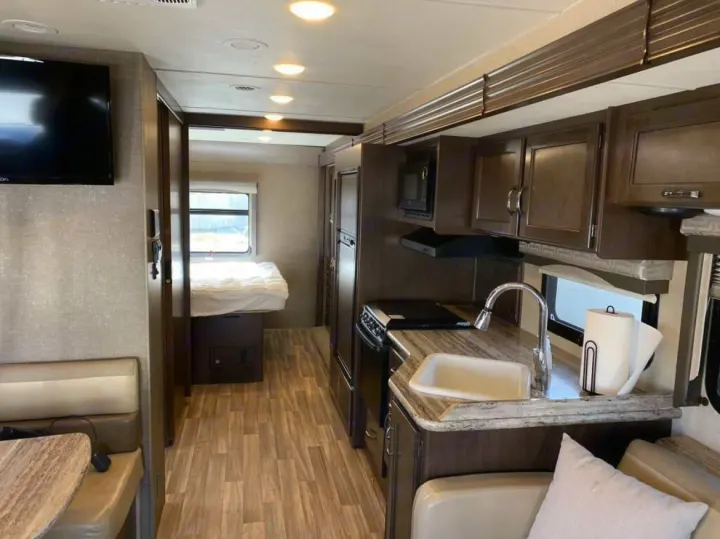 RV rental interior featuring a full kitchen, dining booth, and private bedroom area. Modern and ready for your adventure.. Thor A.C.E. 2016