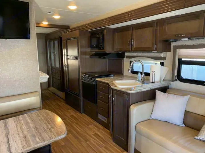 Inside this rv rental: a well-equipped kitchen, dining booth, and sofa, offering comfortable living space for road trips.. Thor A.C.E. 2016
